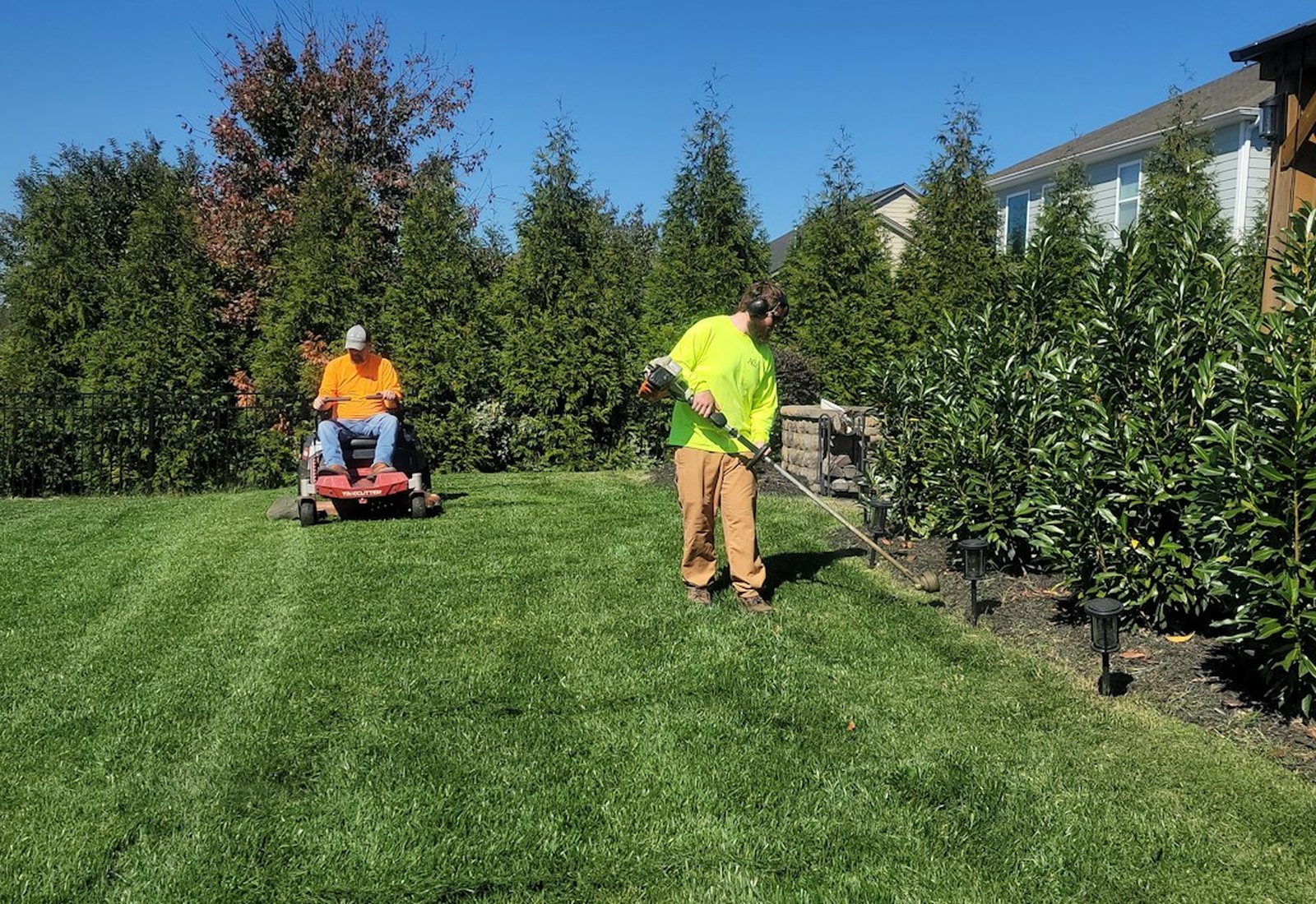 Lawn care professionals maintaining a broad residential yard